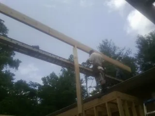 Carpenter setting a ridge beam over a new addition frame — Ice Dam Removal by Roofing Brothers in Halethorpe