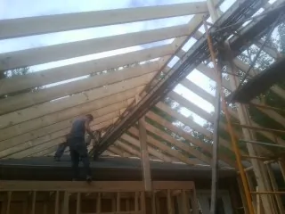 Rafters going up over a new addition with a worker on the wall in Halethorpe