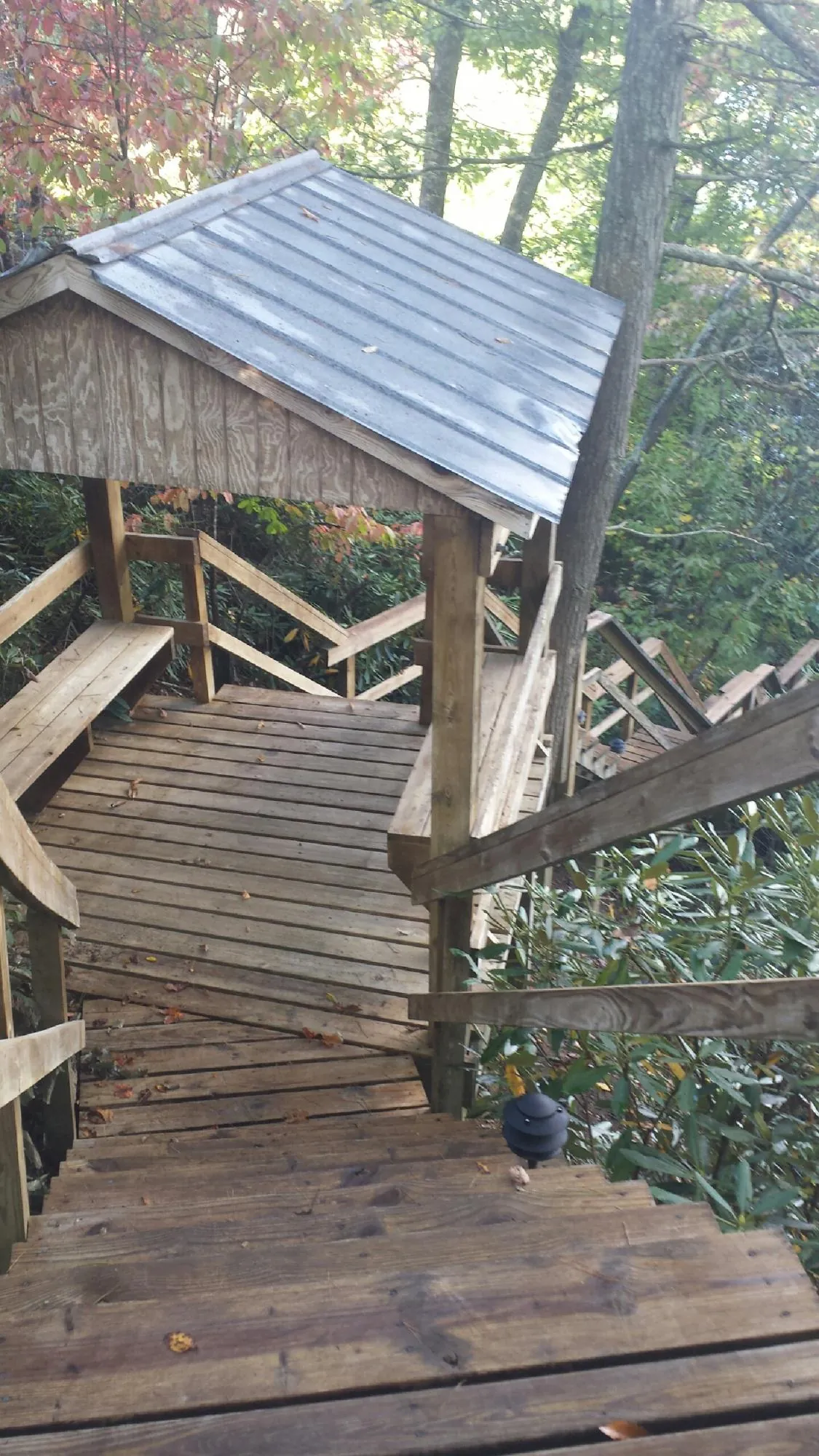 Metal roofed shelter over wooden steps on a wooded walkway — Skylight Repair & Installation work by our crew in Halethorpe