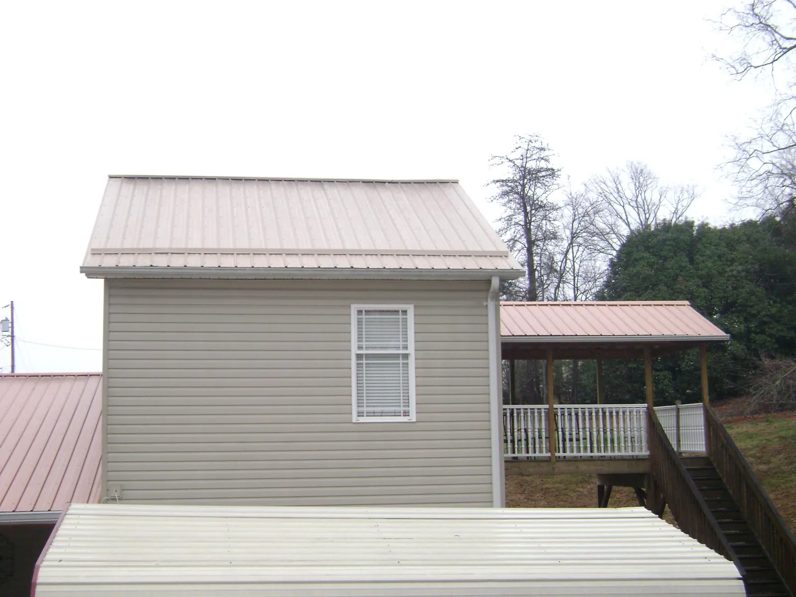 Tan metal roofs on a two story addition and attached porch, from a Roof Replacement job in Halethorpe