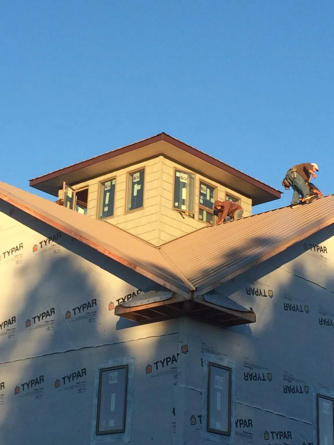 Roofers working around a rooftop cupola on a new metal roof at sunset — Roof Waterproofing in Halethorpe by Roofing Brothers